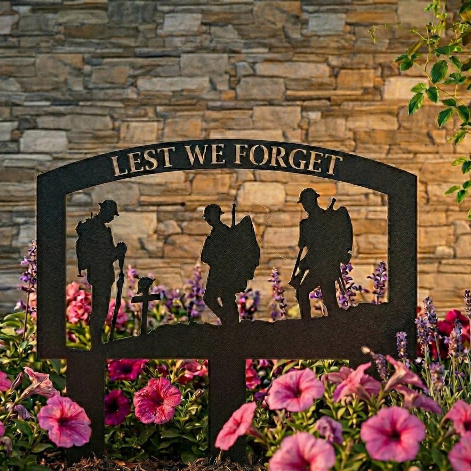 Decorative metal sign with silhouettes of soldiers and 'Lest We Forget' text, set against a stone wall and floral background.