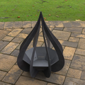 Black metal fire pit on a stone patio with grass in the background